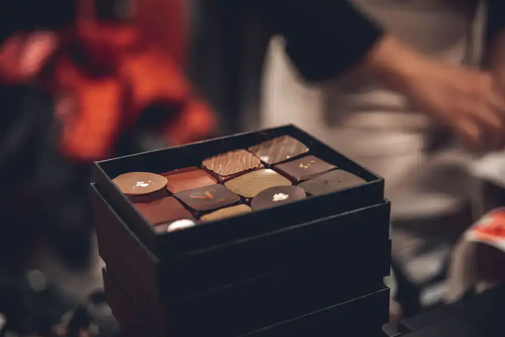 Chocolatier carefully placing chocolates into a presentation box